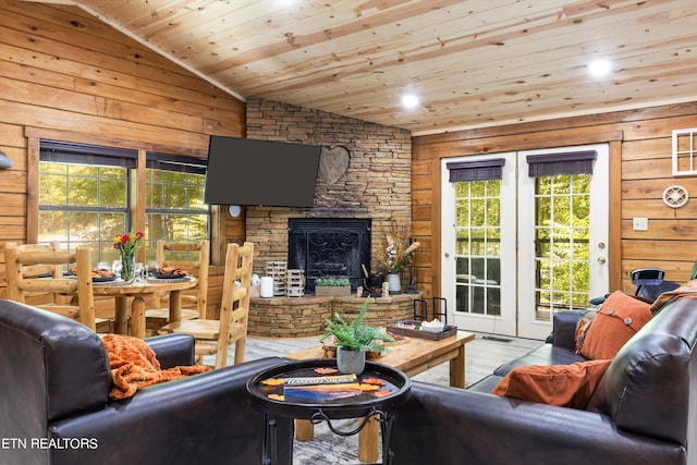 living room with lofted ceiling, a stone fireplace, wooden walls, and wooden ceiling