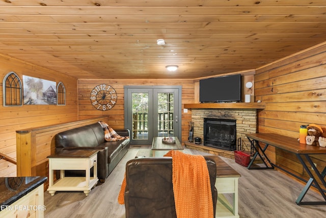 living room with light hardwood / wood-style floors, wooden ceiling, and a fireplace