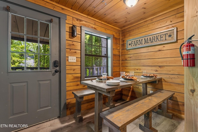 dining room featuring plenty of natural light, hardwood / wood-style floors, wood ceiling, and wooden walls