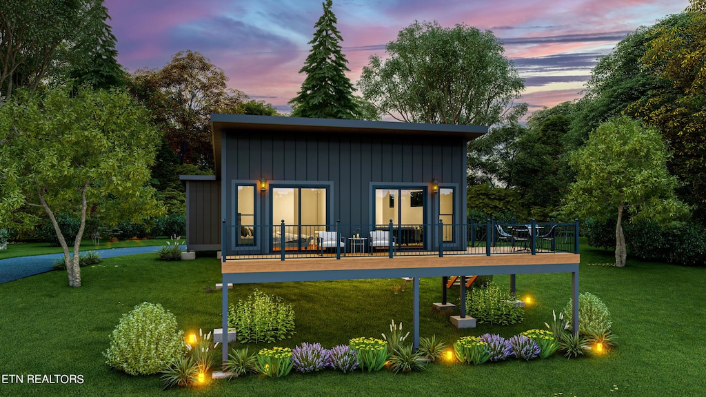 back house at dusk featuring a lawn