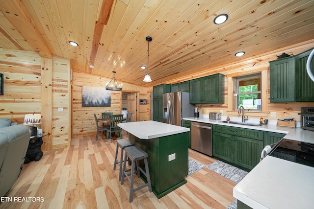 kitchen with appliances with stainless steel finishes, sink, green cabinetry, and pendant lighting