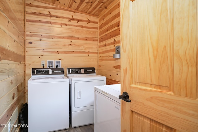 clothes washing area featuring wood ceiling, wood walls, and washing machine and clothes dryer