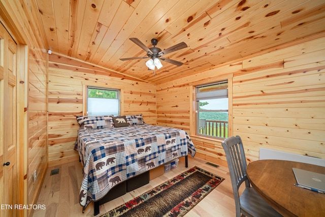 bedroom with ceiling fan, multiple windows, wood ceiling, and wooden walls