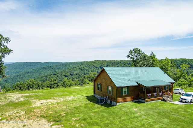 view of property exterior featuring a porch, cooling unit, and a lawn