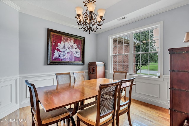 dining area with light wood-type flooring, a notable chandelier, and crown molding