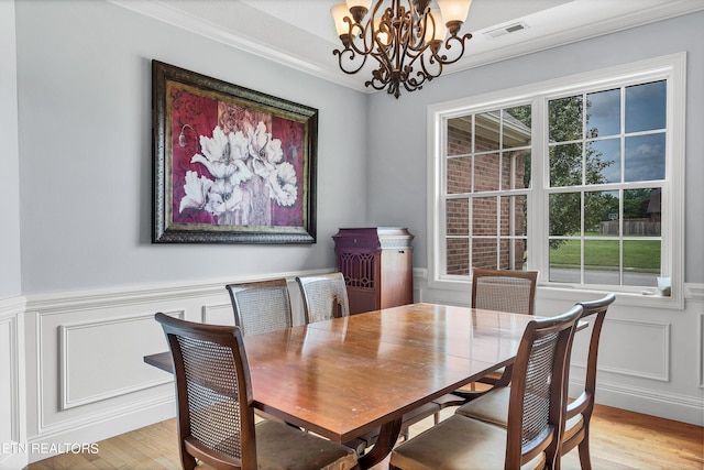 dining area featuring light wood-type flooring, crown molding, and a notable chandelier