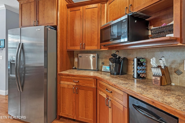 kitchen featuring decorative backsplash, light hardwood / wood-style flooring, light stone countertops, appliances with stainless steel finishes, and ornamental molding