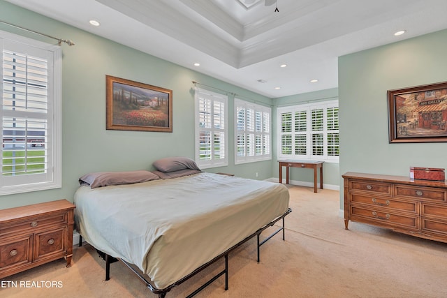 bedroom with a raised ceiling, light colored carpet, crown molding, and multiple windows