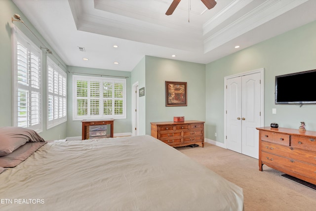 carpeted bedroom featuring ceiling fan, a tray ceiling, and ornamental molding