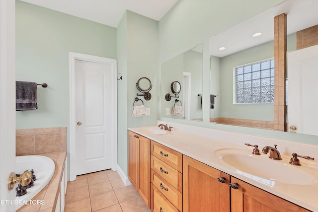 bathroom featuring tiled tub, vanity, and tile patterned flooring