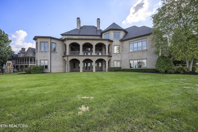 back of property with a balcony and a yard