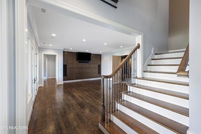 stairway with ornamental molding and wood-type flooring