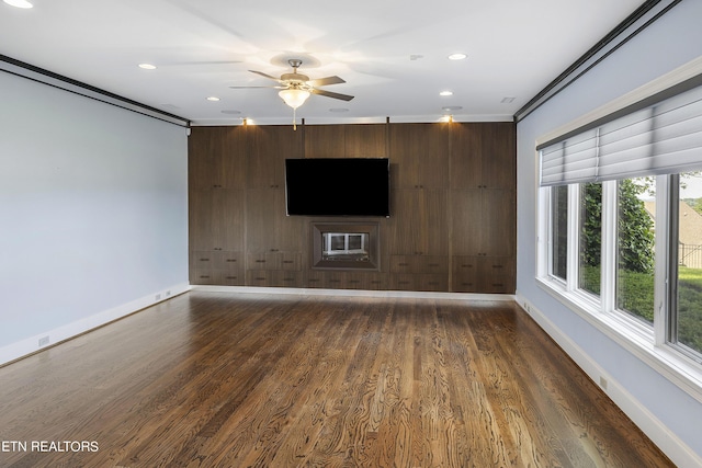 unfurnished living room with dark wood-type flooring, ceiling fan, ornamental molding, and wooden walls