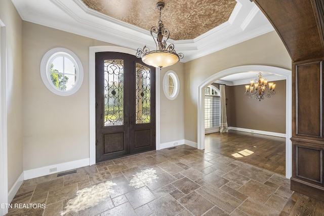 foyer entrance featuring french doors, a raised ceiling, an inviting chandelier, and crown molding