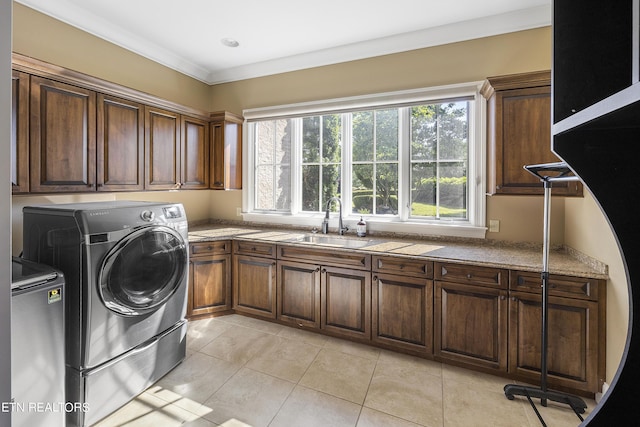 clothes washing area featuring light tile patterned floors, cabinets, crown molding, washing machine and clothes dryer, and sink