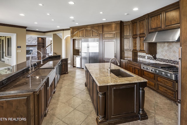 kitchen with sink, stainless steel appliances, a spacious island, decorative backsplash, and dark brown cabinetry