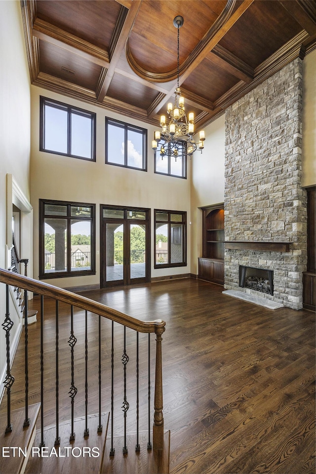 unfurnished living room featuring wood ceiling, an inviting chandelier, beam ceiling, coffered ceiling, and a stone fireplace