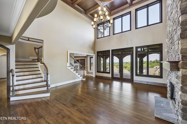 entryway with dark hardwood / wood-style floors, french doors, an inviting chandelier, ornamental molding, and a stone fireplace