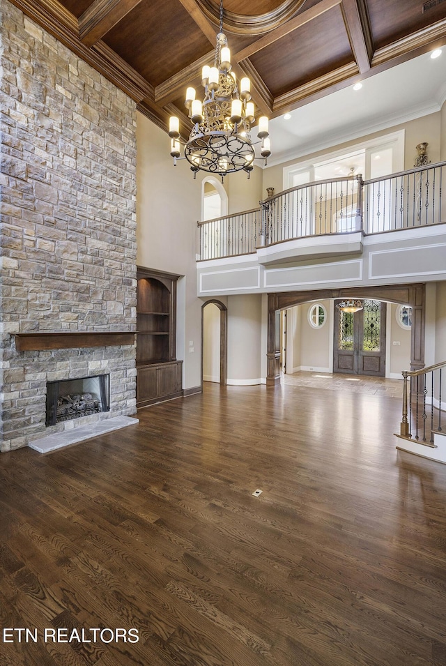 unfurnished living room with wooden ceiling, beamed ceiling, ornamental molding, coffered ceiling, and a stone fireplace