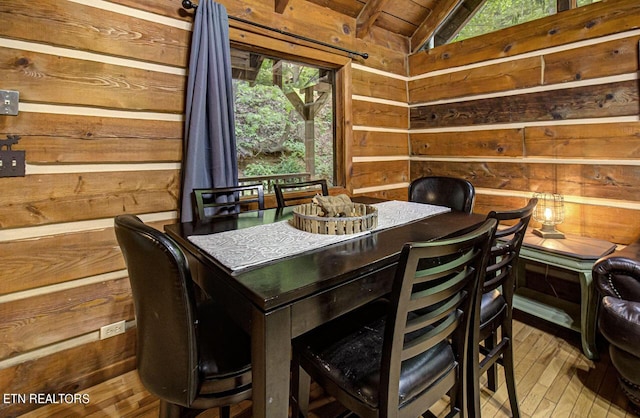 dining room with wood walls, light hardwood / wood-style flooring, wood ceiling, and vaulted ceiling