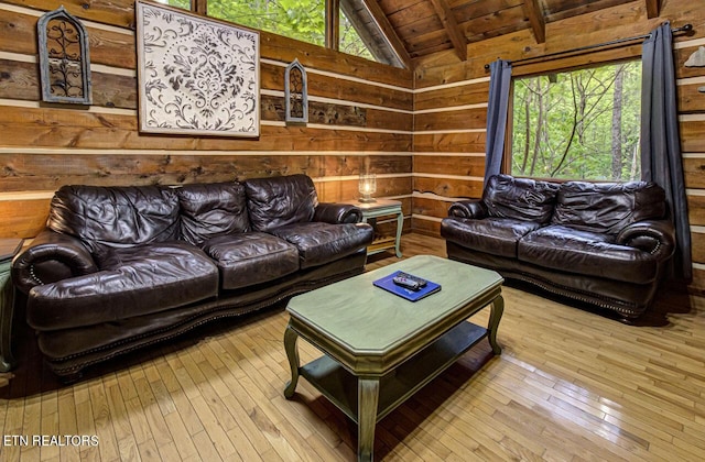 living room with wooden walls, lofted ceiling with beams, light wood-type flooring, and wood ceiling