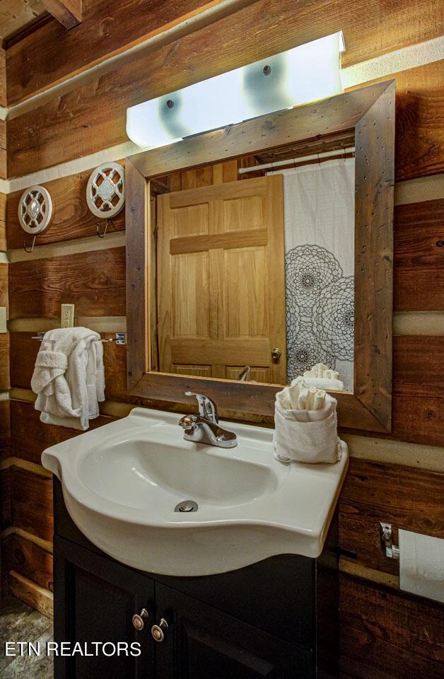 bathroom with vanity, wood walls, and walk in shower