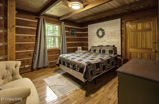 bedroom featuring beam ceiling, light wood-type flooring, wooden walls, and wooden ceiling