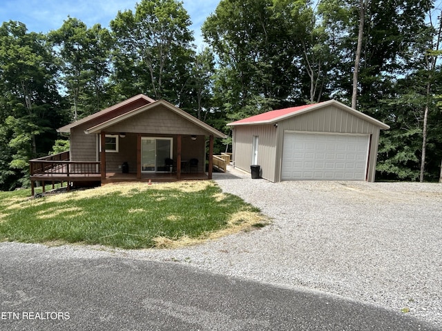 ranch-style house with a deck, a garage, an outbuilding, and a front lawn