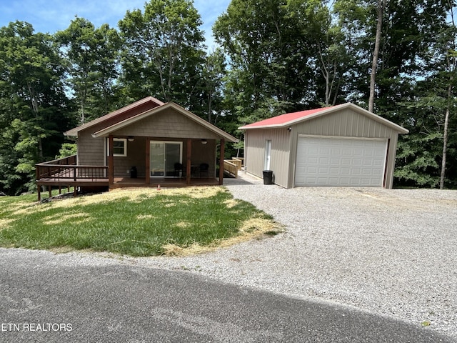 view of front facade with an outbuilding, a front yard, a wooden deck, and a garage