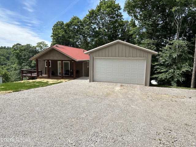 ranch-style house with a deck, a garage, and an outbuilding