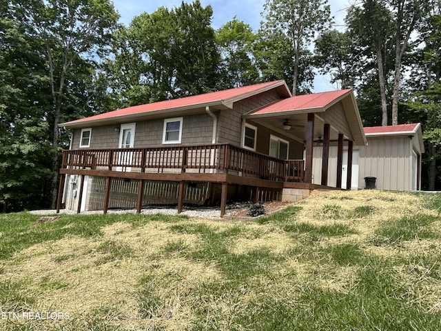 rear view of property with ceiling fan, a wooden deck, and a yard