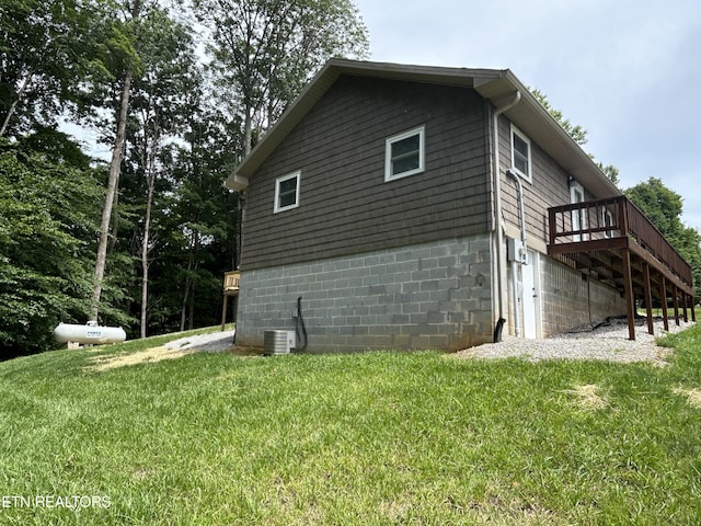 view of property exterior with a lawn, central air condition unit, and a wooden deck