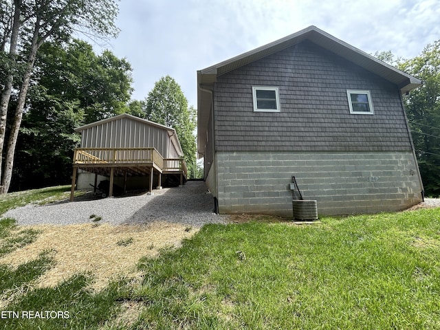 view of side of home featuring a deck, central AC, and a lawn