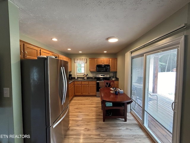 kitchen featuring a textured ceiling, stainless steel appliances, and light wood-type flooring