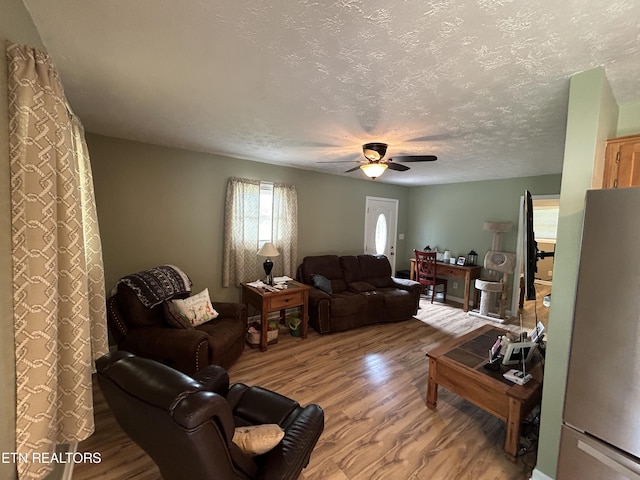 living room with ceiling fan, wood-type flooring, and a textured ceiling