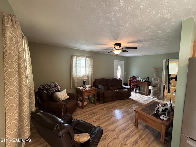 living room featuring ceiling fan, wood-type flooring, and a textured ceiling