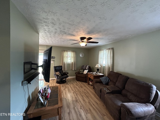 living room with a textured ceiling, ceiling fan, and wood-type flooring