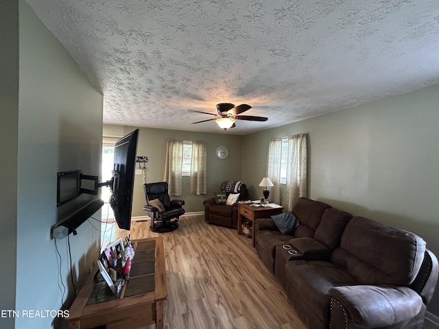 living room with ceiling fan, wood-type flooring, and a textured ceiling