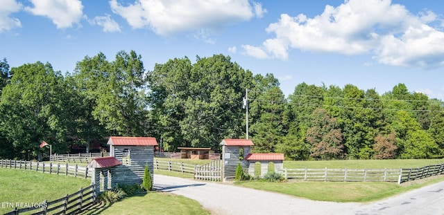 view of community with a rural view, a lawn, and a shed