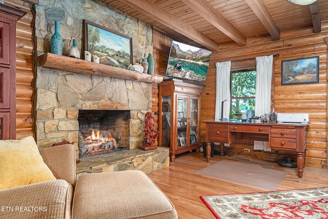 interior space with beamed ceiling, rustic walls, light wood-type flooring, wood ceiling, and a stone fireplace