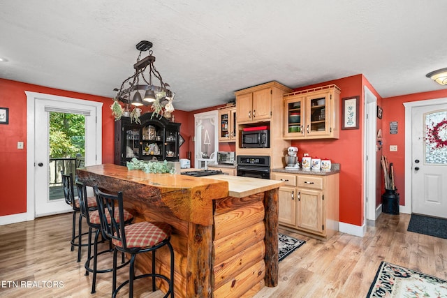 kitchen featuring light hardwood / wood-style floors, decorative light fixtures, a textured ceiling, and black appliances