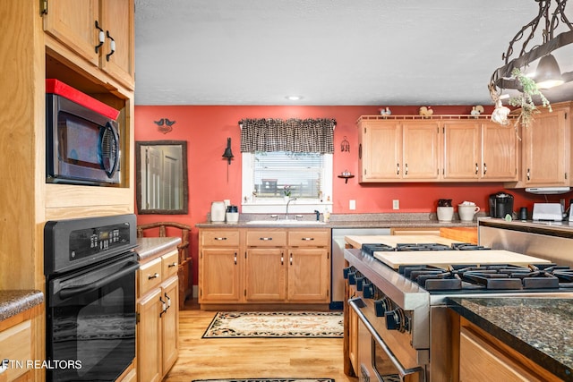 kitchen featuring light wood-type flooring, appliances with stainless steel finishes, decorative light fixtures, and sink