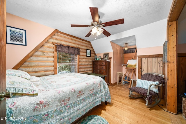 bedroom with ceiling fan, vaulted ceiling, light wood-type flooring, a textured ceiling, and log walls