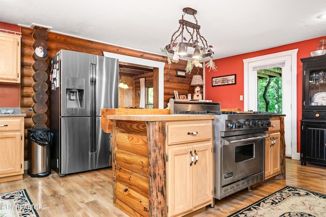 kitchen with appliances with stainless steel finishes, light brown cabinetry, log walls, hanging light fixtures, and light hardwood / wood-style flooring