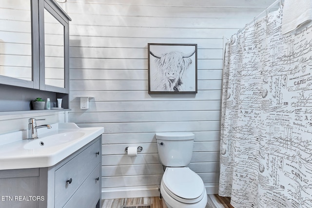 bathroom with hardwood / wood-style floors, vanity, a shower with shower curtain, and toilet