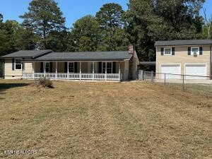 back of property with a garage, a porch, and a lawn