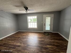 spare room with ceiling fan, a textured ceiling, and dark wood-type flooring