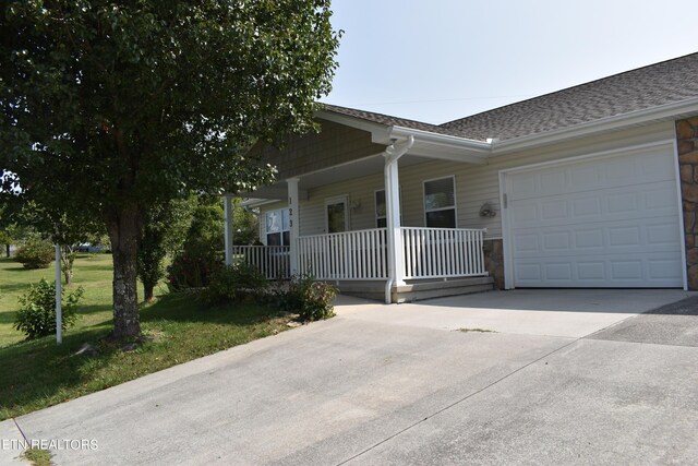 ranch-style house with a porch, a garage, and a front yard