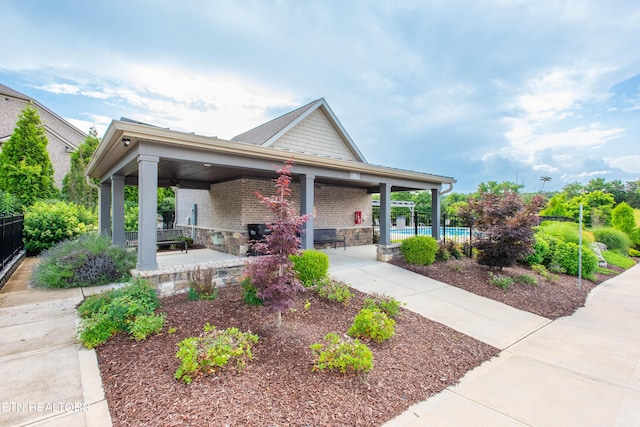 view of front of house with brick siding, fence, and an outdoor pool