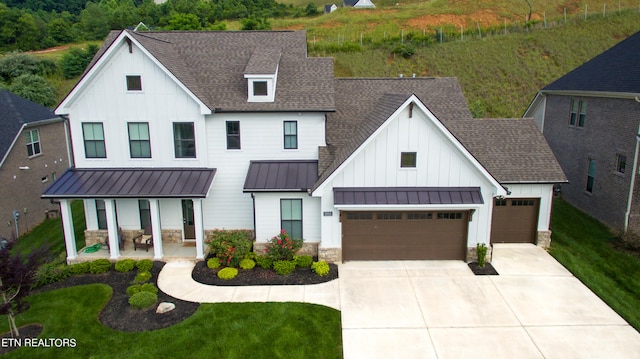 modern farmhouse with a front lawn, covered porch, and a garage